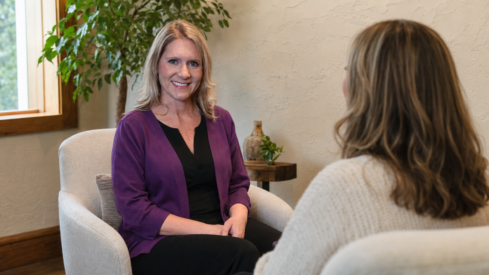 Dr. Diane Otness seated in a softly lit room, listening attentively during a consultation with a client